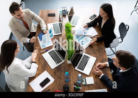 Un gruppo di uomini d'affari su un grande desktop che discute di trattative commerciali vista dall'alto Foto Stock