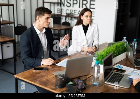 Trattative aziendali in ufficio su un grande desktop tra dipendenti di aziende diverse Foto Stock