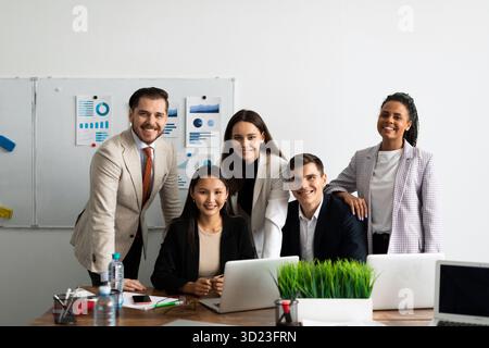 Il personale sorridente dell'azienda, composto da giovani professionisti internazionali e multietnici, con un dirigente più anziano, guarda la videocamera Foto Stock