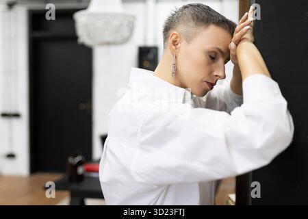 Stanca donna d'affari appoggiata al muro con gli occhi chiusi riposati Foto Stock