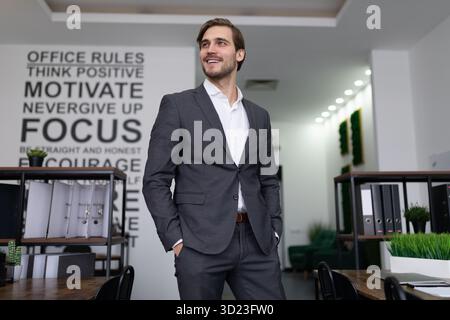 Un uomo d'affari caucasico di successo ispeziona con un sorriso il suo ufficio di un'azienda di successo Foto Stock