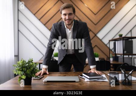 Un uomo d'affari dà il benvenuto ai nuovi dipendenti in ufficio guardando la telecamera Foto Stock