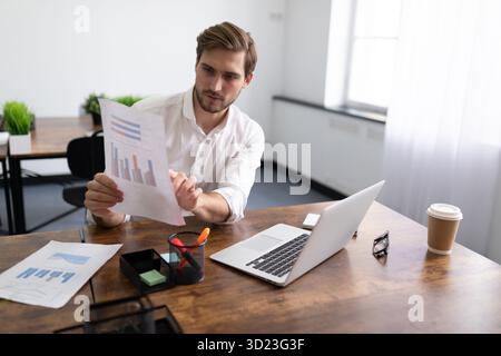 Uomo d'affari in abiti da lavoro che tiene una riunione su un notebook e dimostra la crescita dei profitti su un grafico Foto Stock