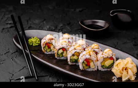 Panini di sushi con verdure fresche serviti su un elegante piatto nero Foto Stock
