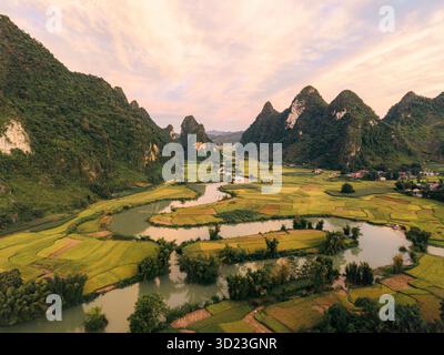 Lussureggiante valle verde con un fiume tortuoso circondato da montagne spettacolari sotto un cielo morbido. Phong Nam, TR˘ng KH·nh District, Cao Bang, Vietnam Foto Stock