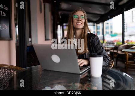 Giovane freelance che lavora su un notebook in remoto in un bar Foto Stock