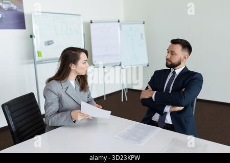 Riunione nella sala riunioni di due dipendenti aziendali in tute aziendali, concetto di negoziazione aziendale di successo Foto Stock