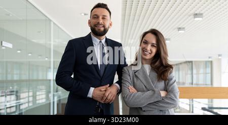 Colleghi uomini e donne in abiti da lavoro sullo sfondo dello spazio per uffici, concetto di servizi immobiliari Foto Stock