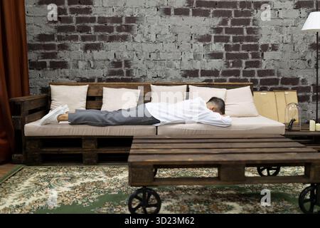 Stanca e stanca mentre una donna d'affari si sdraia sul divano a casa Foto Stock