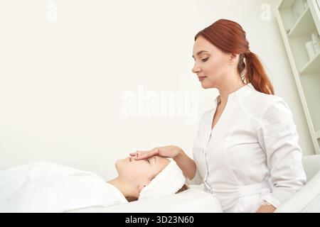 Estetista caucasica femminile che esegue un trattamento facciale rilassante su giovani Foto Stock