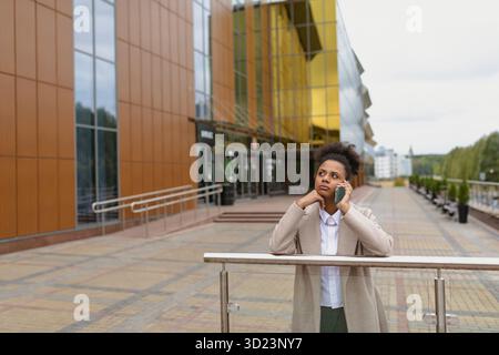Una seria donna d'affari afroamericana che parla al telefono fuori Foto Stock