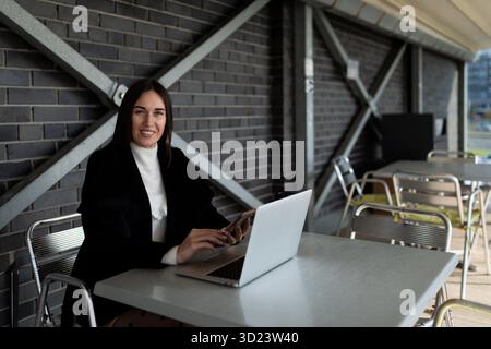 Agente immobiliare donna di successo che lavora su un notebook online seduto a tavola Foto Stock