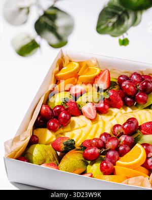 Vassoio di frutta fresca con fragole, uva e arance per l'evento estivo Foto Stock