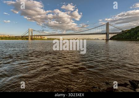 Il maestoso ponte sospeso attraversa il fiume sotto un cielo pieno di nuvole sparse al tramonto. New York City, New York, USA George Washington Bridge, fiume Hudson Foto Stock