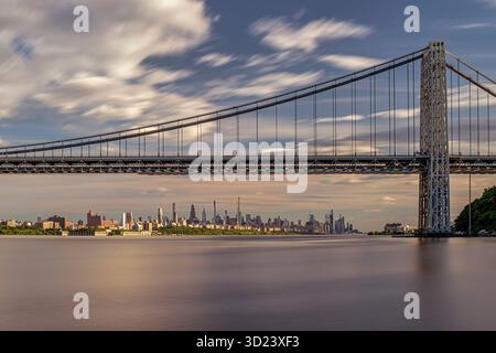 Splendido ponte sospeso con skyline della città sotto un cielo dinamico pieno di nuvole al tramonto. New York City, New York, USA George Washington Bridge, fiume Hudson Foto Stock