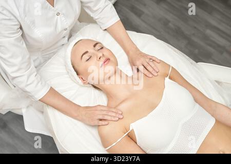 Donna caucasica adulta che riceve un massaggio rilassante alle spalle e al collo nella spa Foto Stock