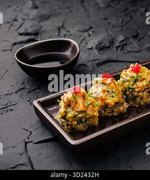 Piatto di sushi con condimenti colorati servito su sfondo di pietra scura Foto Stock