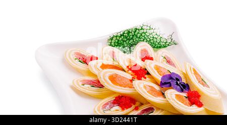 Delicati pancake, sushi roll disposti ad arte su un piatto decorativo Foto Stock