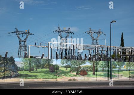 Sottostazione elettrica o cantiere con piloni elettrici, trasformatori e recinzione di sicurezza decorata o verniciata o recinzione di sicurezza Foto Stock