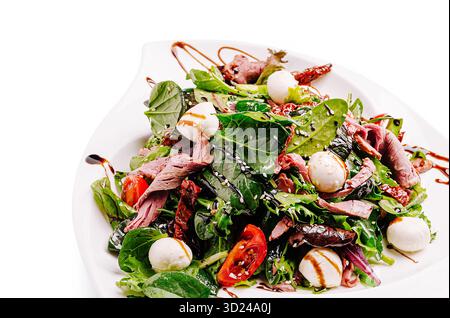 Insalata fresca con verdure, pomodori e mozzarella su piatto bianco Foto Stock