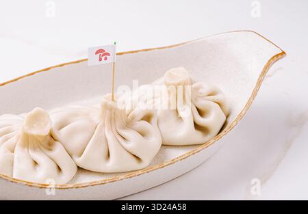 Tre gnocchi di khinkali tradizionali georgiani serviti in un piatto di ceramica. Foto Stock