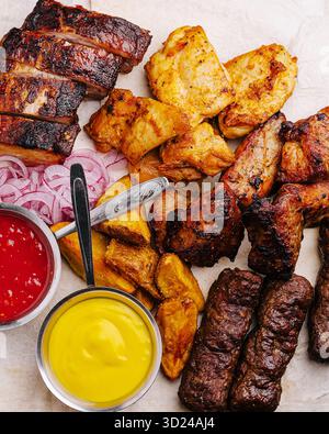 Deliziose carni alla griglia con salse e contorni serviti su un piatto Foto Stock