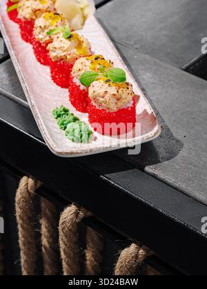Piatto di sushi dai colori vivaci servito su un moderno tavolo nero Foto Stock
