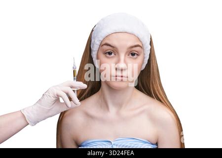 Giovane donna caucasica che riceve un'iniezione cosmetica da un professionista con guanti Foto Stock