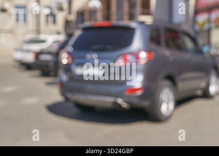 Immagine sfocata dei suv parcheggiati in un ambiente urbano con particolare attenzione al veicolo grigio Foto Stock