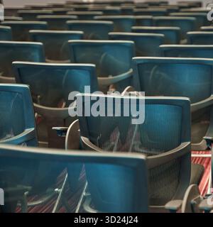 Sala conferenze vuota piena di sedie blu disposte in modo ordinato in fila Foto Stock