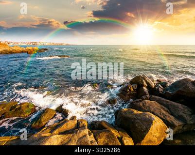 tramonto sulla spiaggia rocciosa. splendida vista sul paesaggio costiero in estate. sole sull'orizzonte e cielo nuvoloso. suggestivo paesaggio con formazioni rocciose Foto Stock