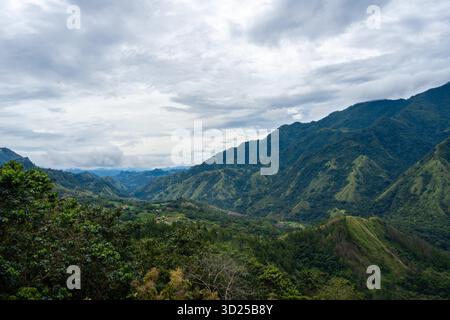 Lussureggianti montagne verdi si estendono attraverso la regione di Toraja a Sulawesi, Indonesia, sotto un cielo nuvoloso con nebbia aggrappata ai ridgelines Foto Stock