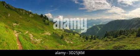 Ampio paesaggio panoramico che mostra una valle verdeggiante circondata da montagne sotto un cielo soleggiato. Questa scena evoca tranquillità e mette in risalto la bellezza di Foto Stock