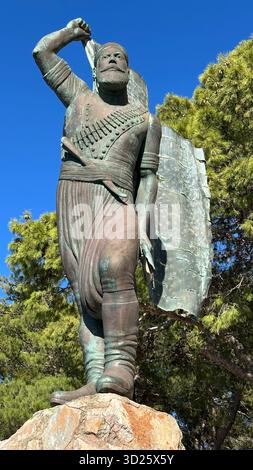 Eroica statua in bronzo di Spyros Kayales che innalza la bandiera greca al parco Venizelos Graves di Akrotiri, Chania, Creta, Grecia, con sfondo marino. Foto Stock