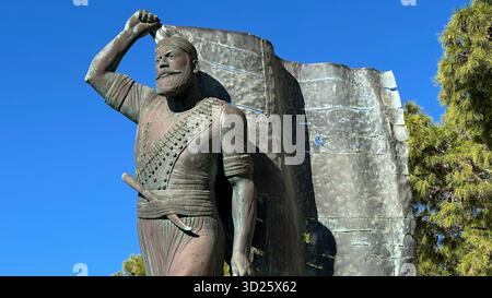 Eroica statua in bronzo di Spyros Kayales che innalza la bandiera greca al parco Venizelos Graves di Akrotiri, Chania, Creta, Grecia, con sfondo marino. Foto Stock