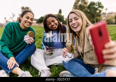 Diverse giovani amiche che si fanno selfie al picnic Foto Stock