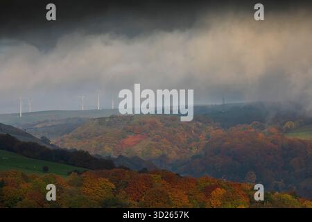I colori autunnali sulla collina Pennine sopra Todmorden, West Yorkshire, come la nebbia di prima mattina avvolge i lontani mulini a vento e le turbine dando alle colline e alle brughiere un aspetto quasi dipinto. Foto Stock