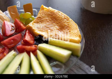 Omelette con verdure fresche, formaggio e uva servite su un piatto di vetro Foto Stock