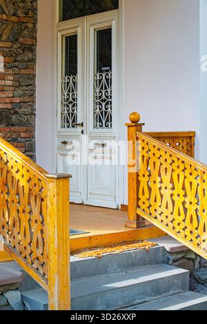La porta d'ingresso di una vecchia casa d'epoca è aperta e i gradini che vi conducono sono in legno Foto Stock