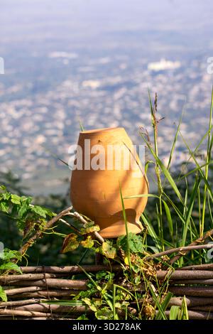 Un'antica caraffa tradizionale in argilla è appesa su una recinzione di legno. Foto Stock