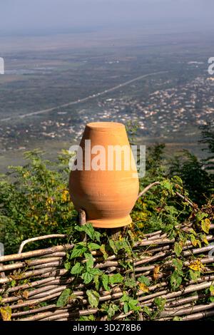 Un'antica caraffa tradizionale in argilla è appesa su una recinzione di legno. Foto Stock