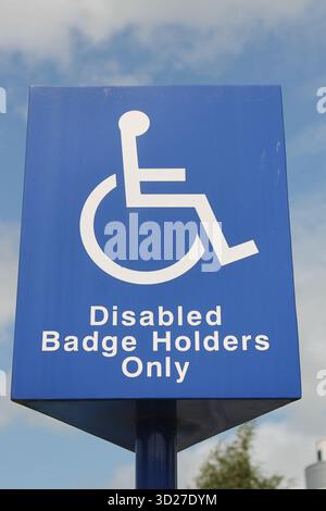 Un segno blu e bianco che mostra uno spazio riservato solo ai proprietari di badge blu disabili Foto Stock