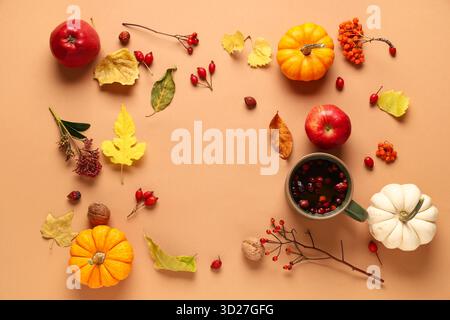 Cornice realizzata con tazza di tè alle bacche caldo, zucche e decorazioni autunnali su sfondo beige Foto Stock