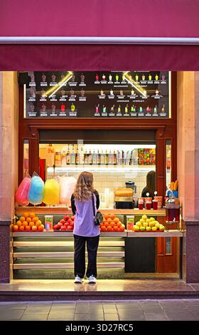 Erevan, Armenia 10.16.2025. Una donna sta davanti a un banco di frutta, guardando il frutto. Il supporto è pieno di arance, mele e altri frutti Foto Stock