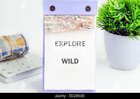 Il calendario mostra Explore Wild accanto ai soldi su una calcolatrice e su una pianta in vaso verde. Suggerisce una pianificazione finanziaria per sostenere l'esplorazione della natura. Foto Stock
