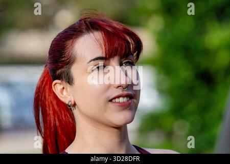 Giovane donna con capelli rossi tinti che esprimono individualità all'aperto Foto Stock