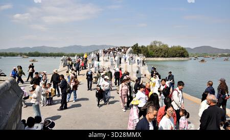 Turisti sul ponte del diciassettesimo arco (Shiqikong Qiao) nel Palazzo d'Estate, complesso di laghi, giardini, padiglioni e palazzi e sito patrimonio dell'umanità dell'UNESCO a Beiji Foto Stock