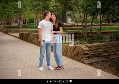 La giovane coppia posa da vicino nel parco urbano e bacia Foto Stock