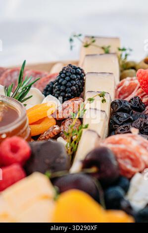 Primo piano di spicchi di formaggio, more e frutta secca a bordo. Foto Stock