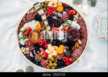 Tagliere rotondo di salumi con formaggio, frutta e carni su un panno Foto Stock